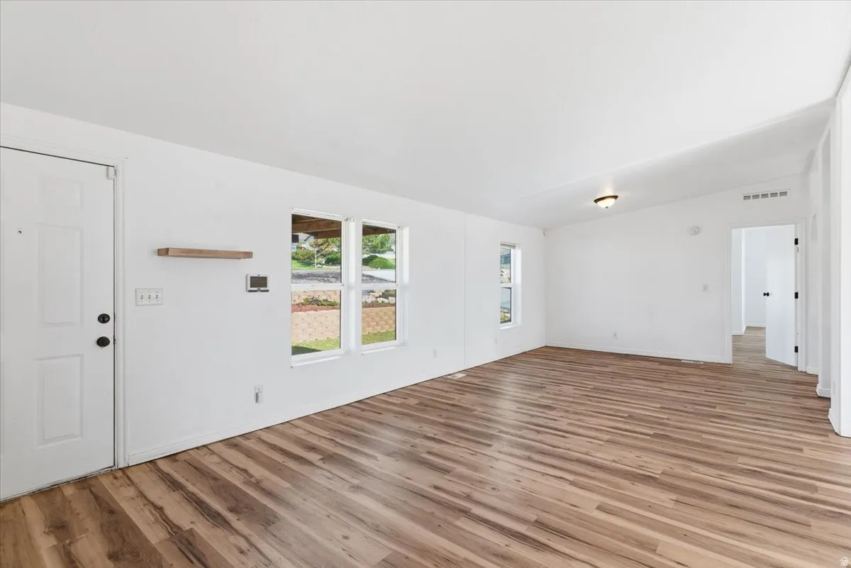 Unfurnished living room with vaulted ceiling and light wood finished floors