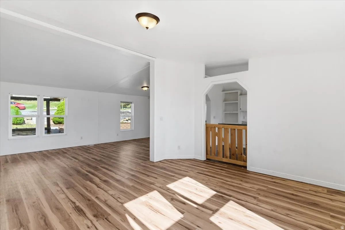 Empty room with wood finished floors and lofted ceiling