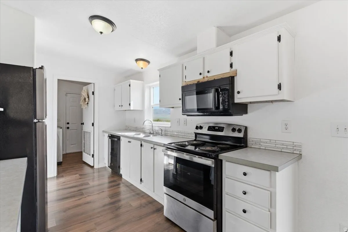 Kitchen with black appliances, light countertops, and white cabinetry