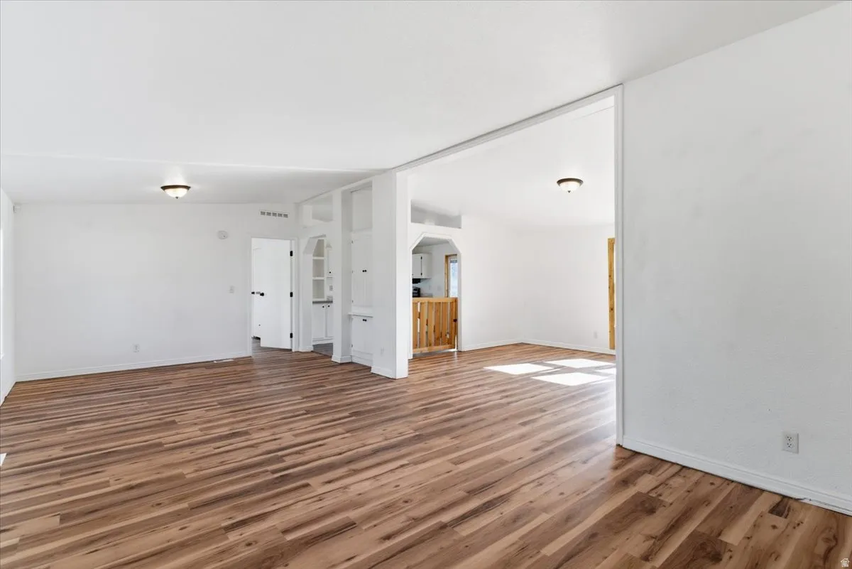 Spare room featuring wood finished floors, arched walkways, and lofted ceiling