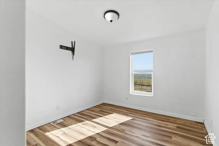 Empty room featuring baseboards and light wood-style flooring