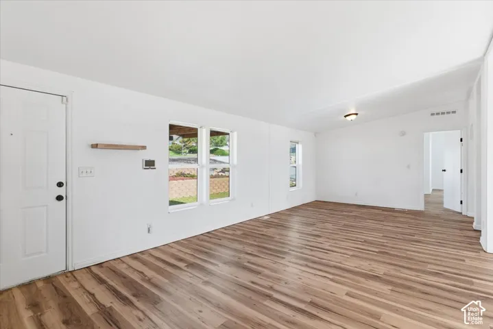Unfurnished living room with vaulted ceiling and light wood finished floors