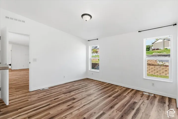 Spare room featuring light wood-style flooring and baseboards