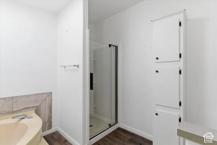 Full bathroom featuring a stall shower, a garden tub, and dark wood-type flooring