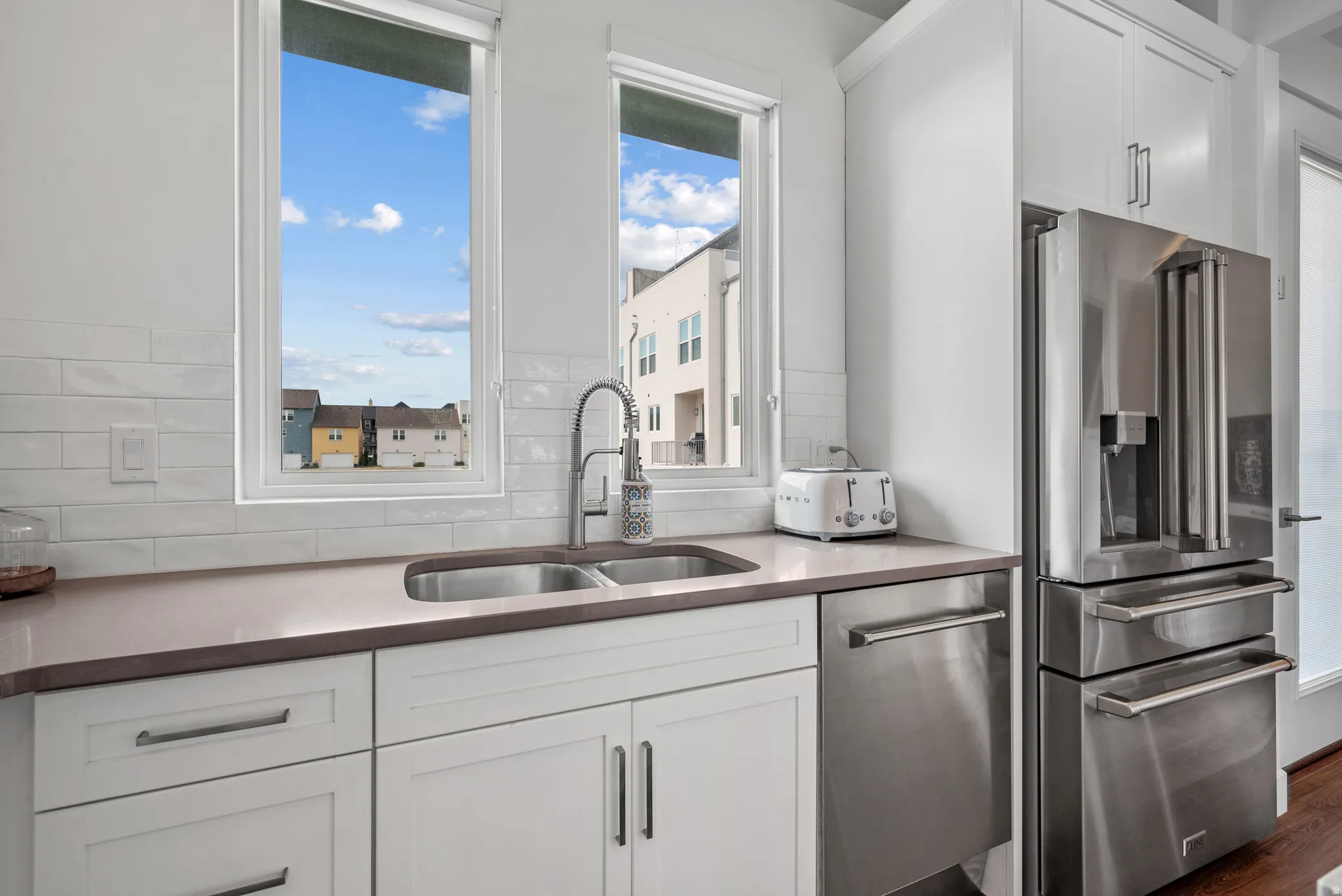 Kitchen featuring white cabinetry, stainless steel appliances, dark stone counters, and dark wood finished floors