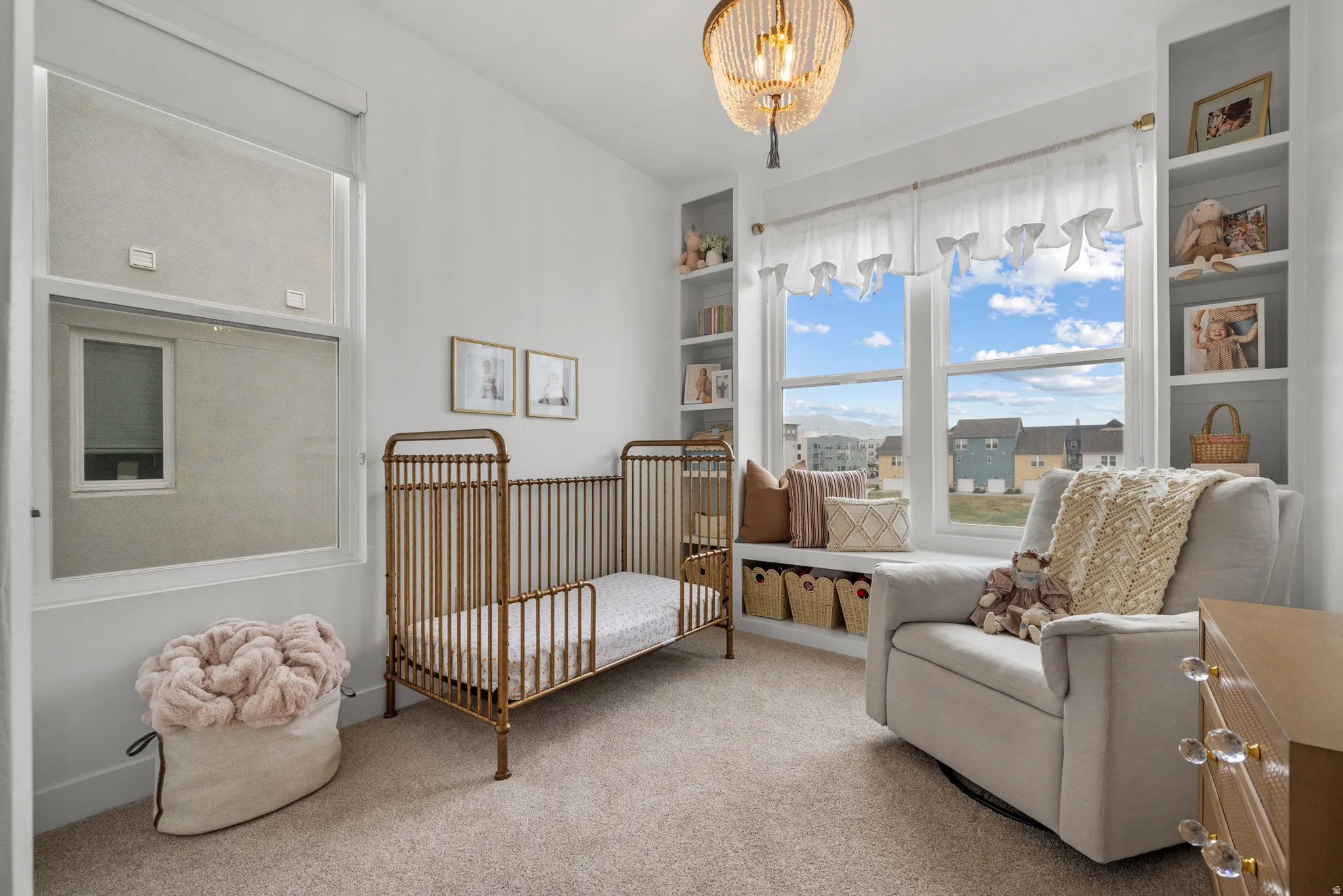 Carpeted bedroom featuring a crib and a chandelier