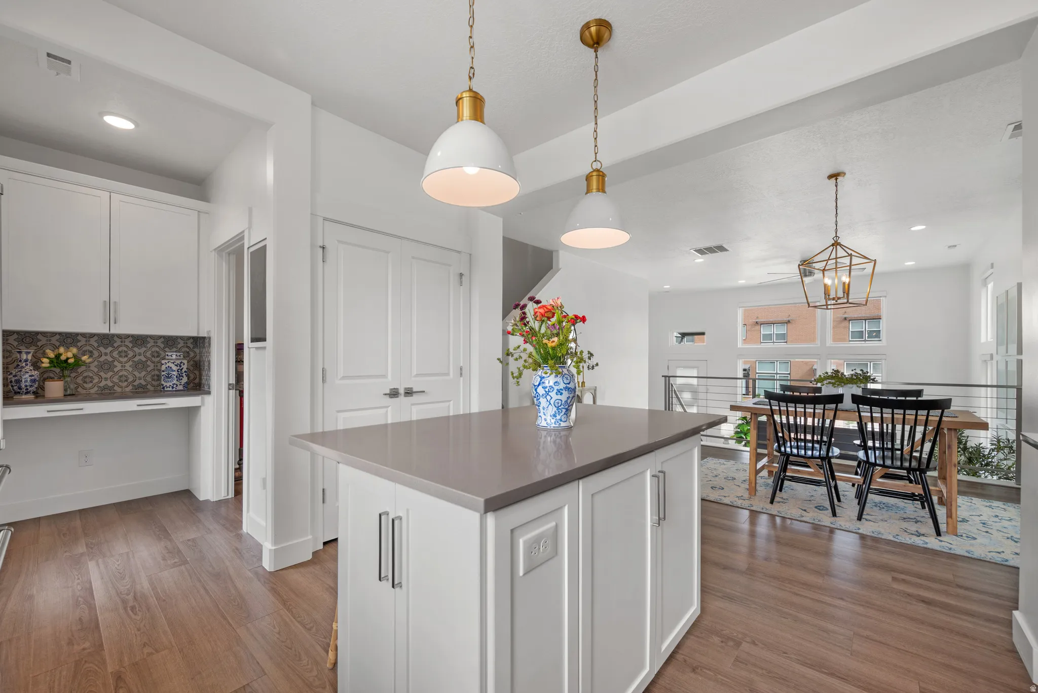 Kitchen with white cabinets, a center island, light wood-style flooring, decorative backsplash, and dark countertops