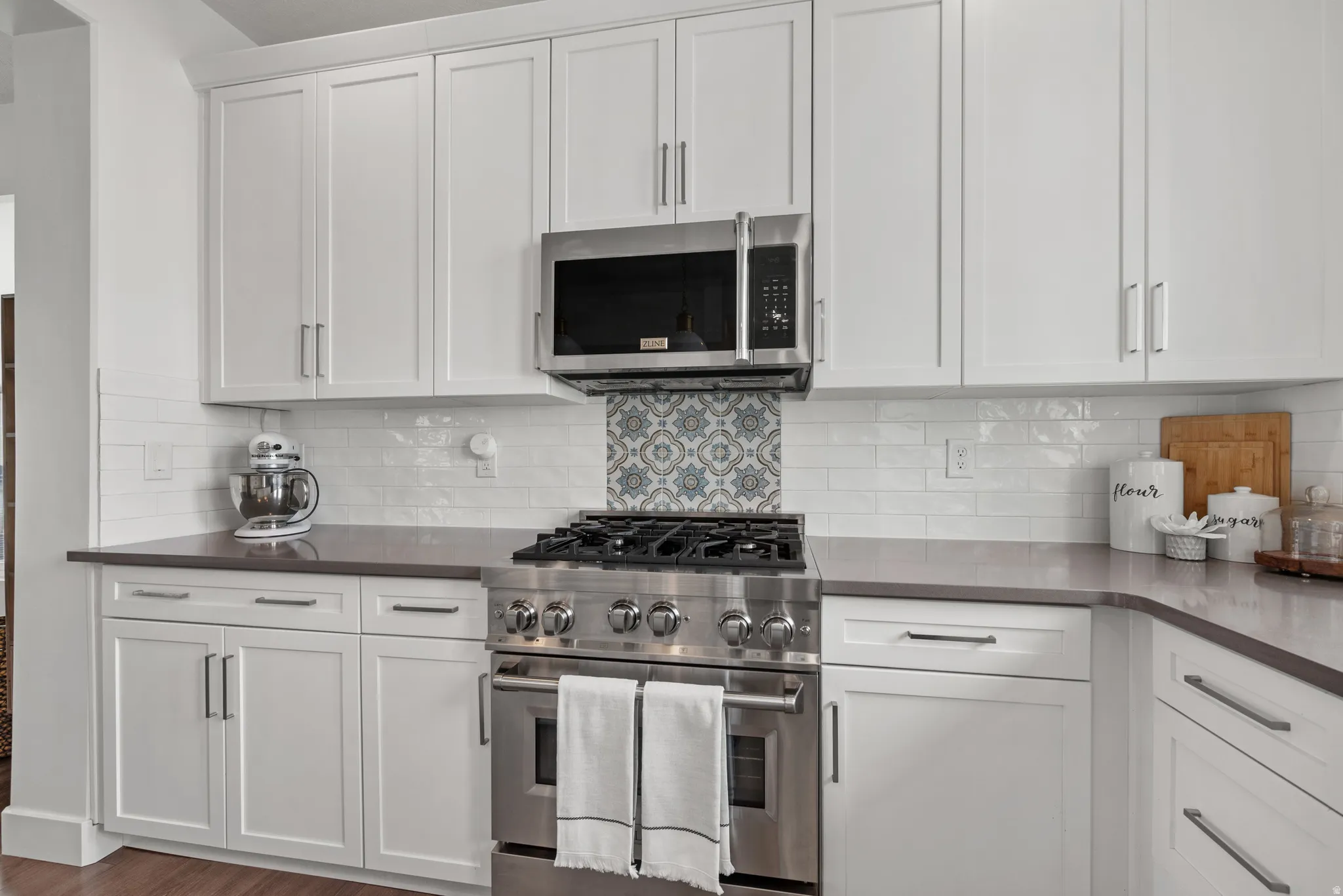 Kitchen featuring stainless steel appliances, white cabinets, backsplash, and wood finished floors