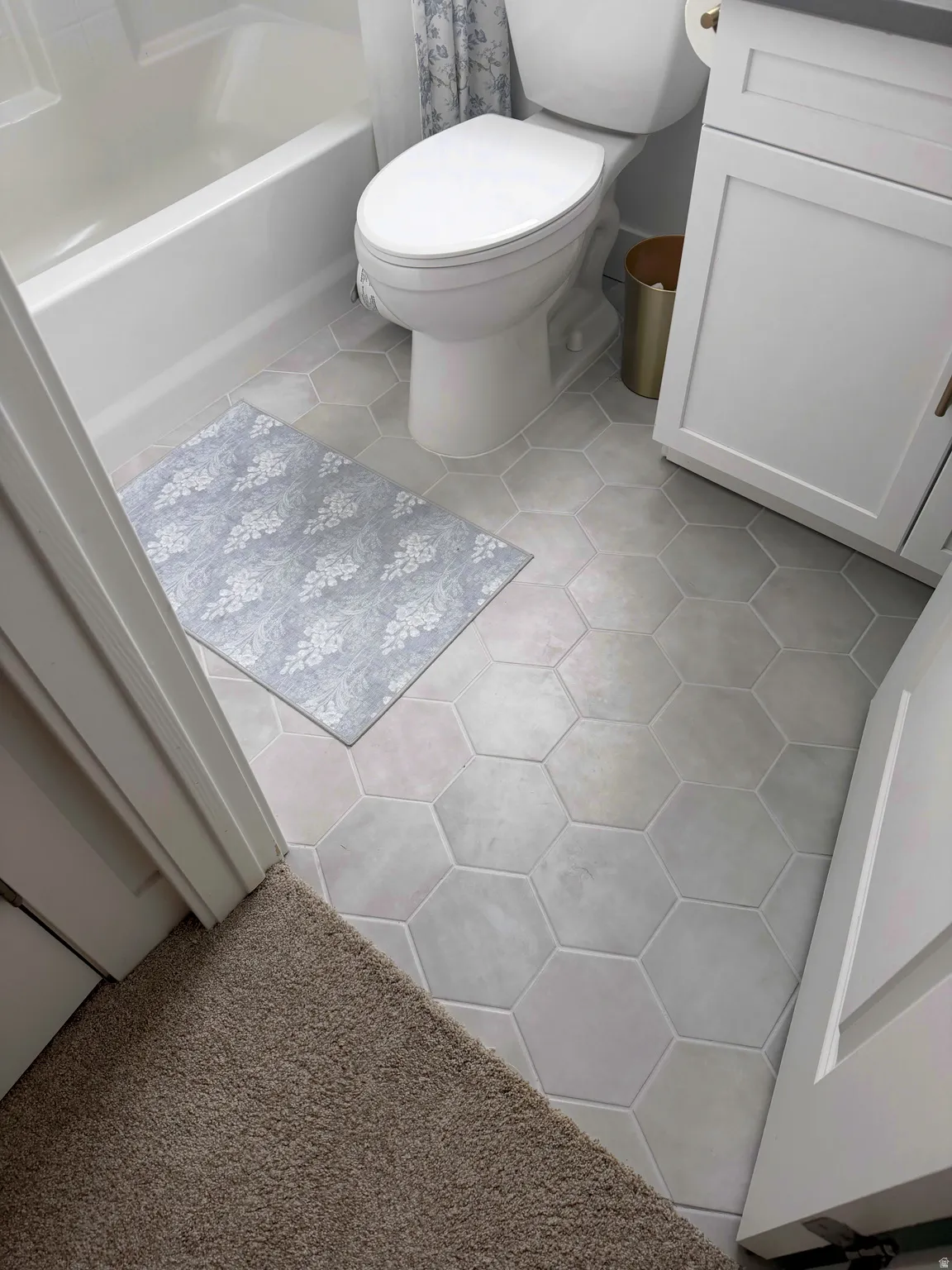 Bathroom featuring light tile patterned floors, vanity, a bathtub, a shower with shower curtain, and light colored carpet