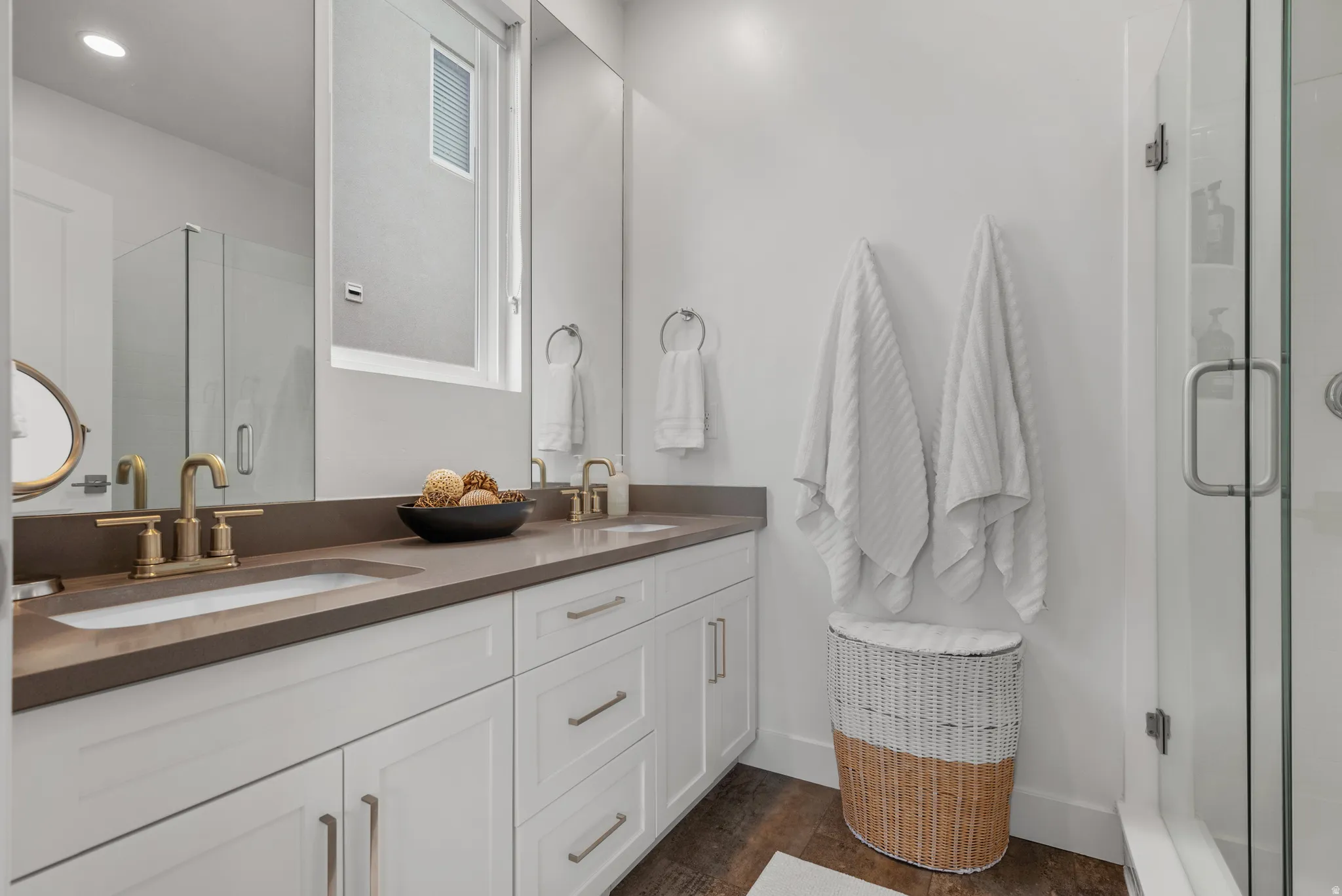 Full bathroom with a stall shower, double vanity, and dark wood finished floors