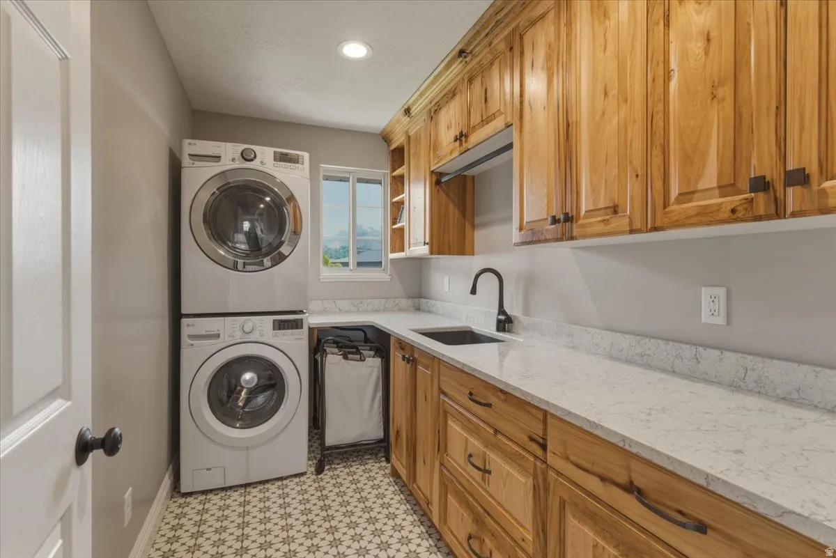 Laundry room with stacked washer / drying machine, recessed lighting, cabinet space, and light flooring