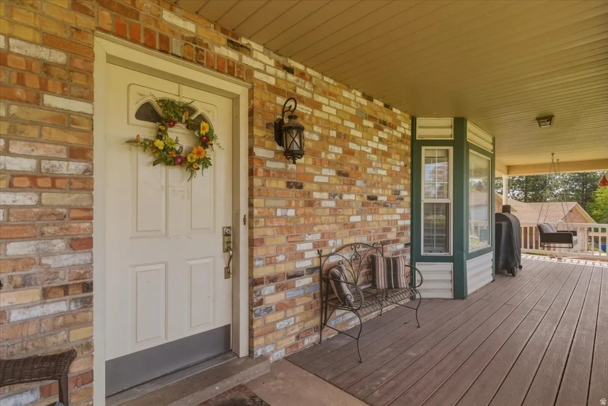 View of exterior entry with covered porch and brick siding