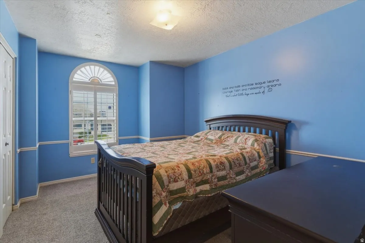 Carpeted bedroom with a textured ceiling and a closet