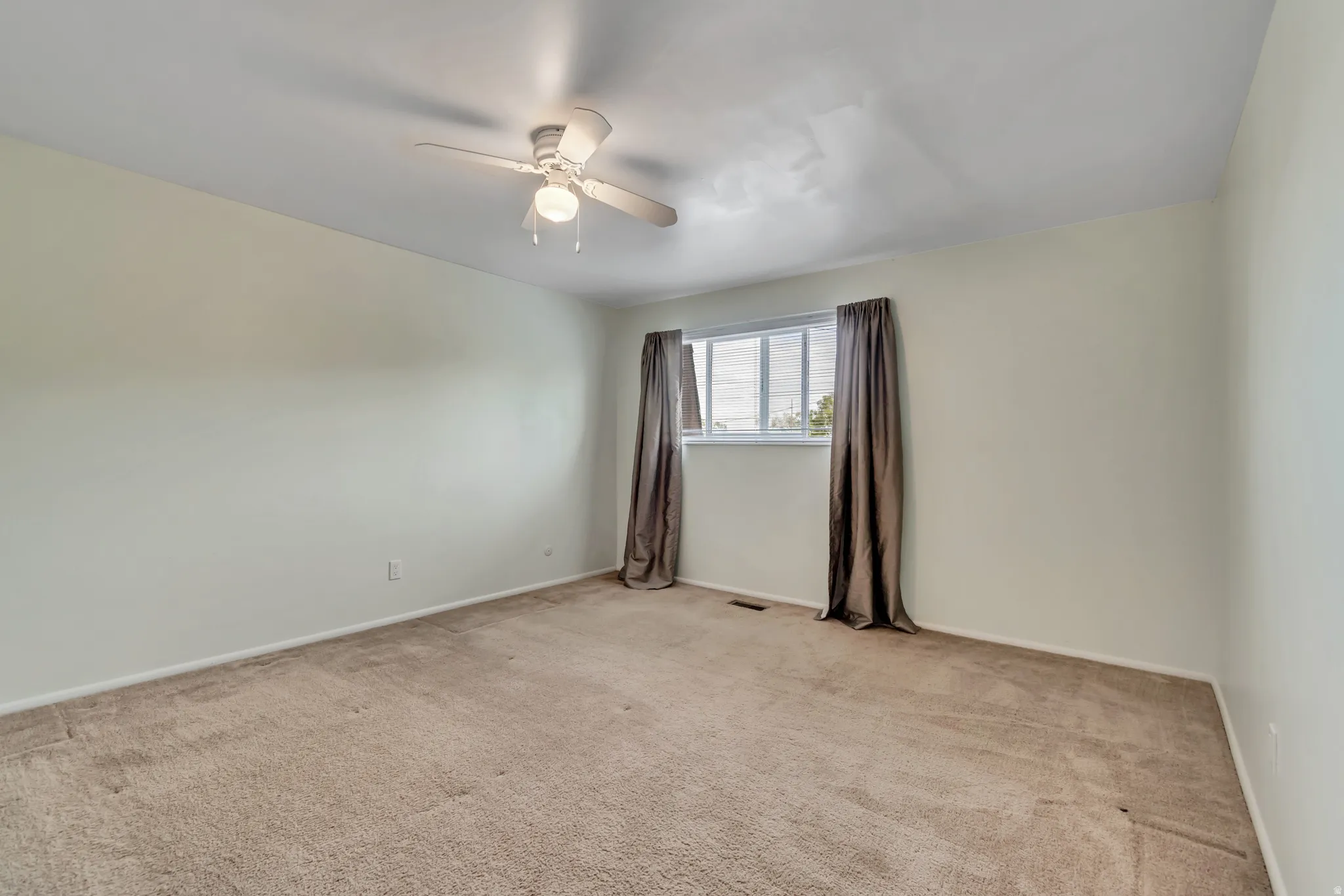Unfurnished room featuring light carpet and ceiling fan