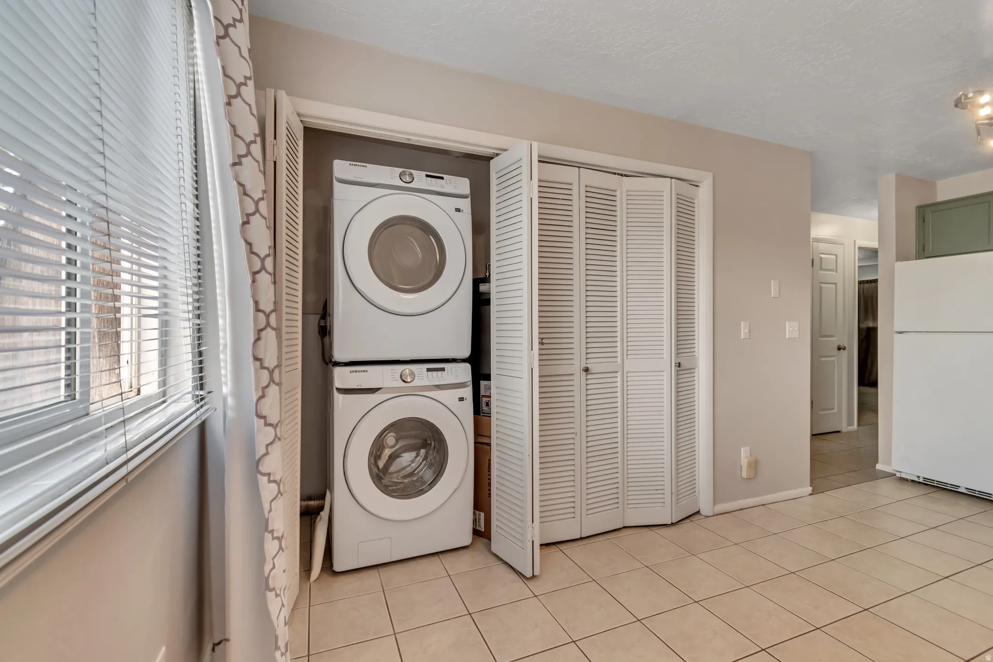 Laundry area featuring stacked washer / dryer and light tile patterned floors