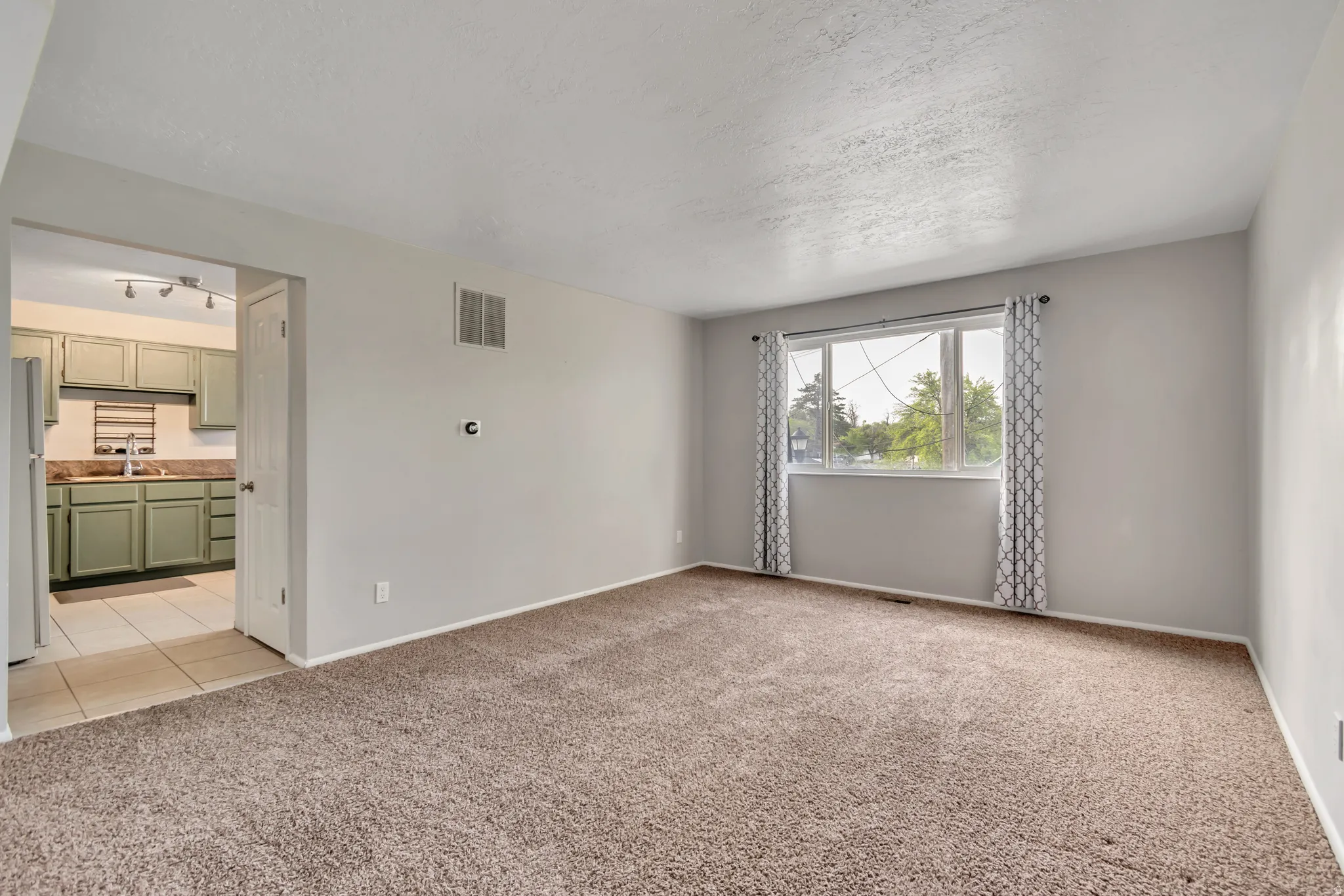 Empty room featuring light carpet and a textured ceiling