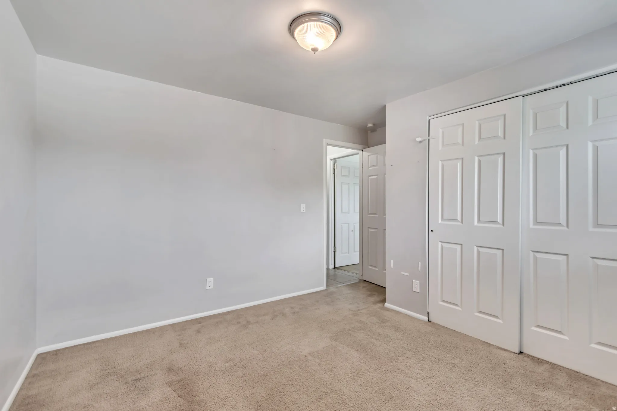 Unfurnished bedroom featuring light carpet and a closet