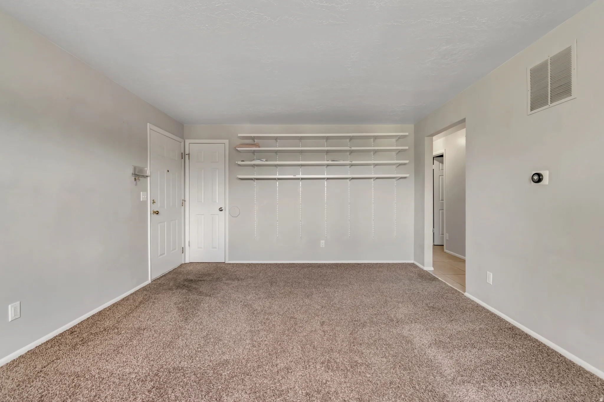 Unfurnished bedroom with light colored carpet and baseboards