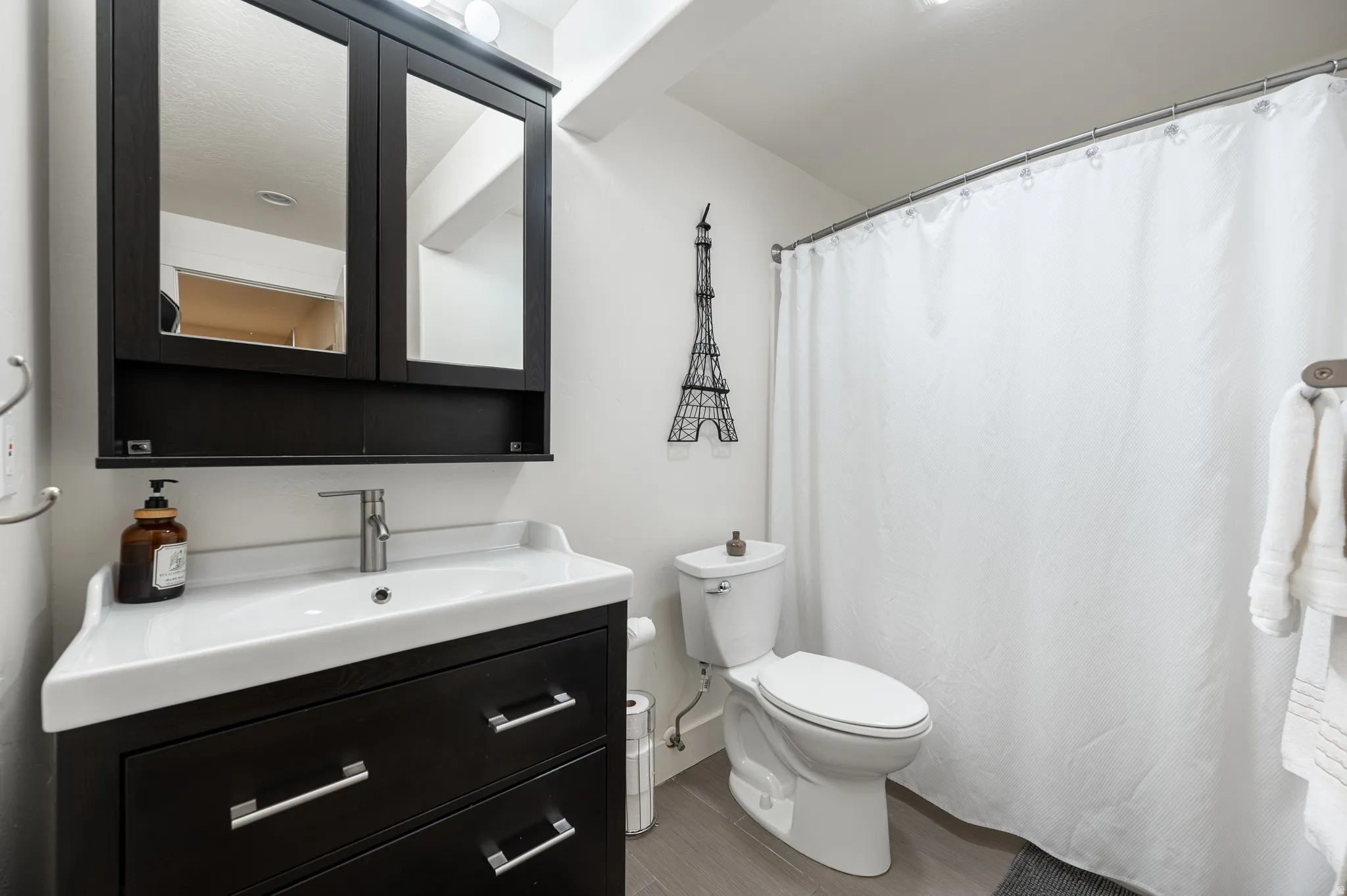 Full bathroom featuring vanity, a shower with curtain, and wood finished floors