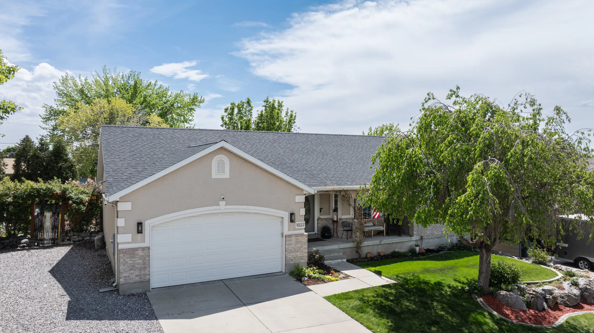 View of front of property with a front lawn, covered porch, driveway, a garage, and a shingled roof