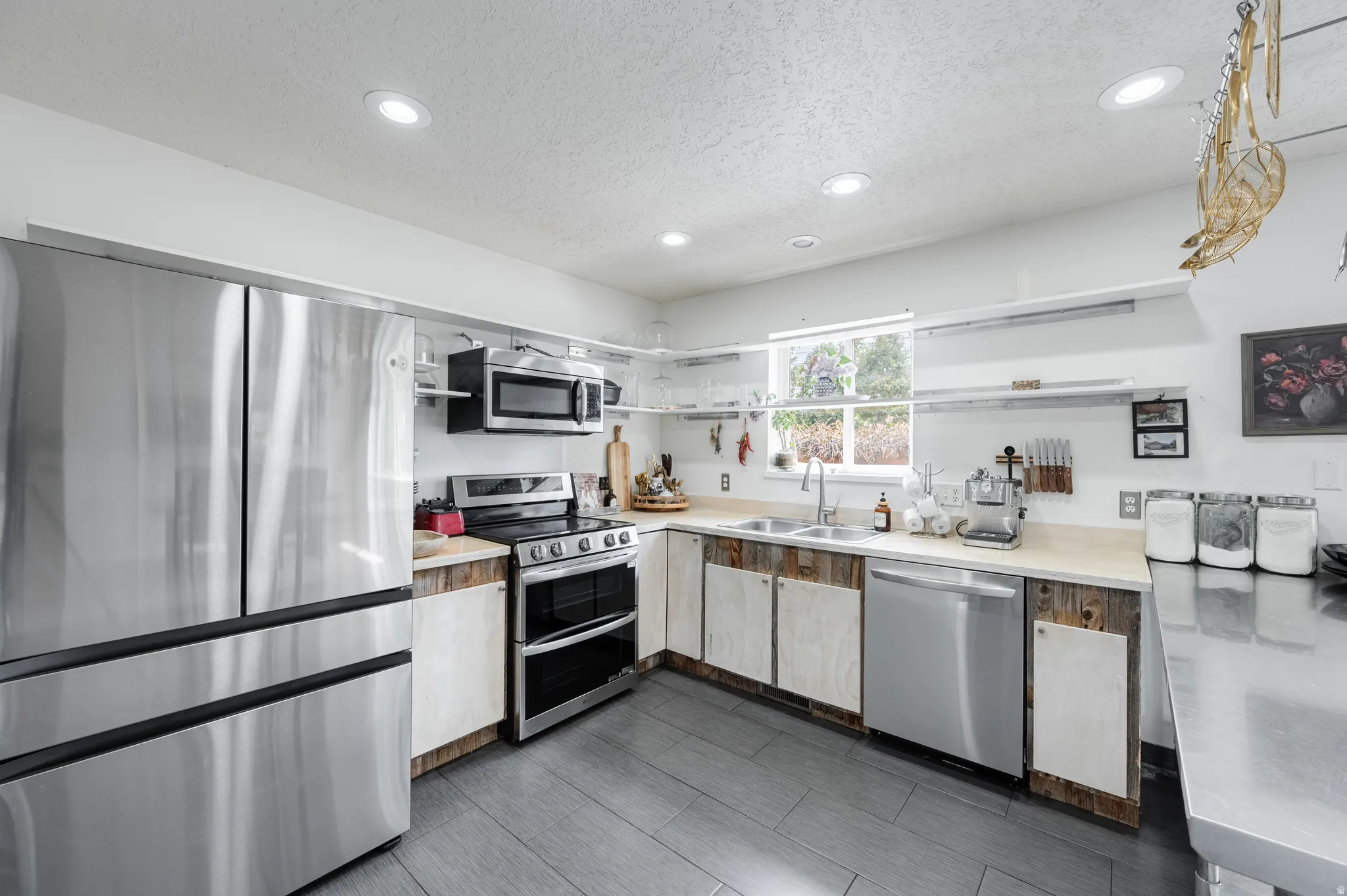 Kitchen featuring stainless steel appliances, light countertops, open shelves, recessed lighting, and a textured ceiling
