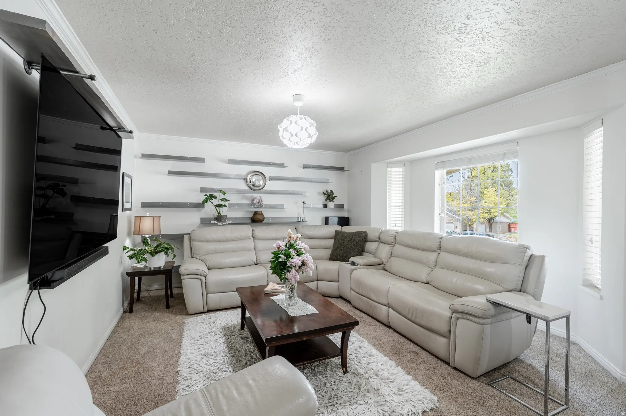 Carpeted living room featuring a textured ceiling and crown molding