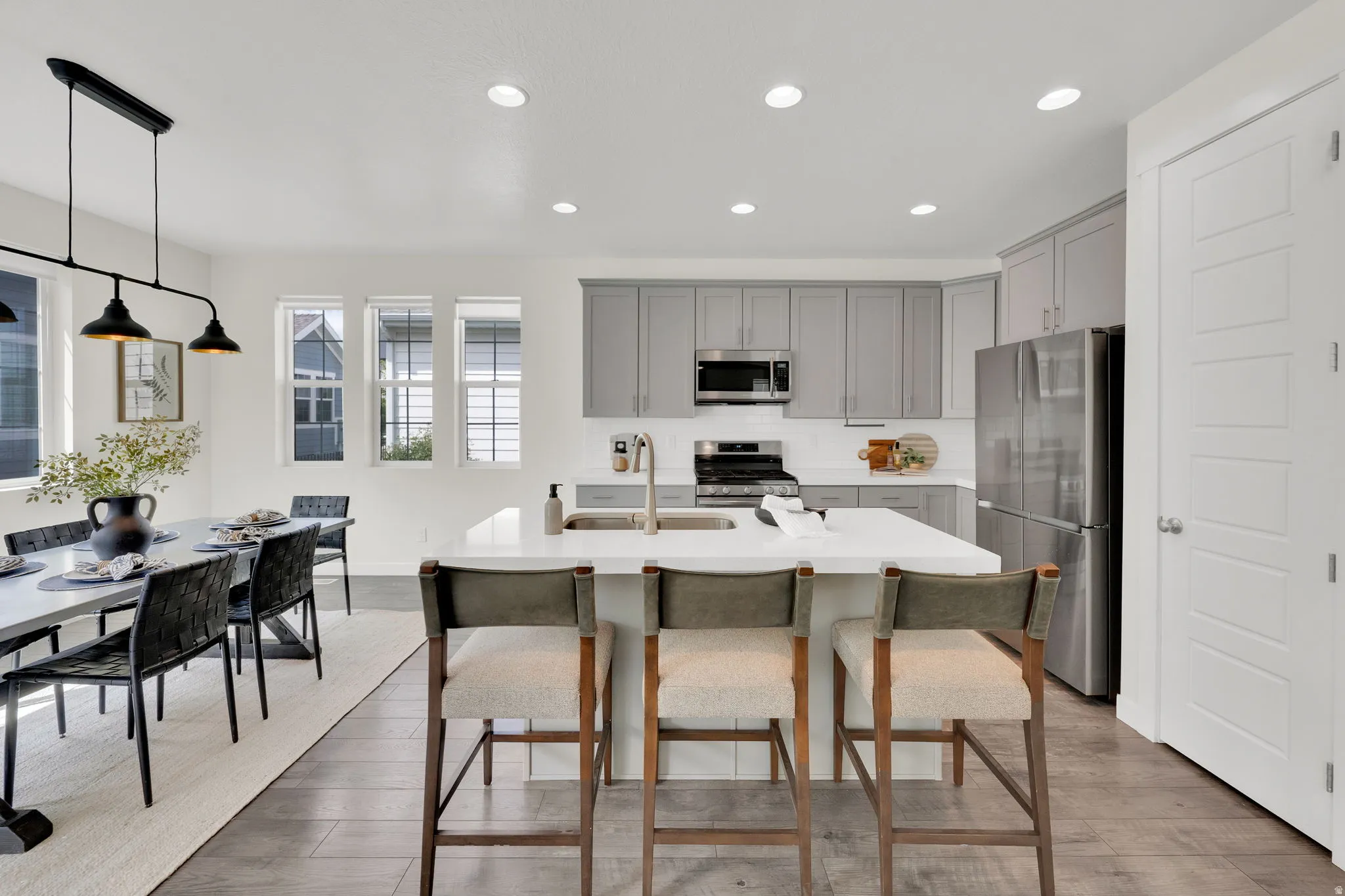Kitchen featuring stainless steel appliances, gray cabinets, an island with sink, a breakfast bar, and light wood-type flooring