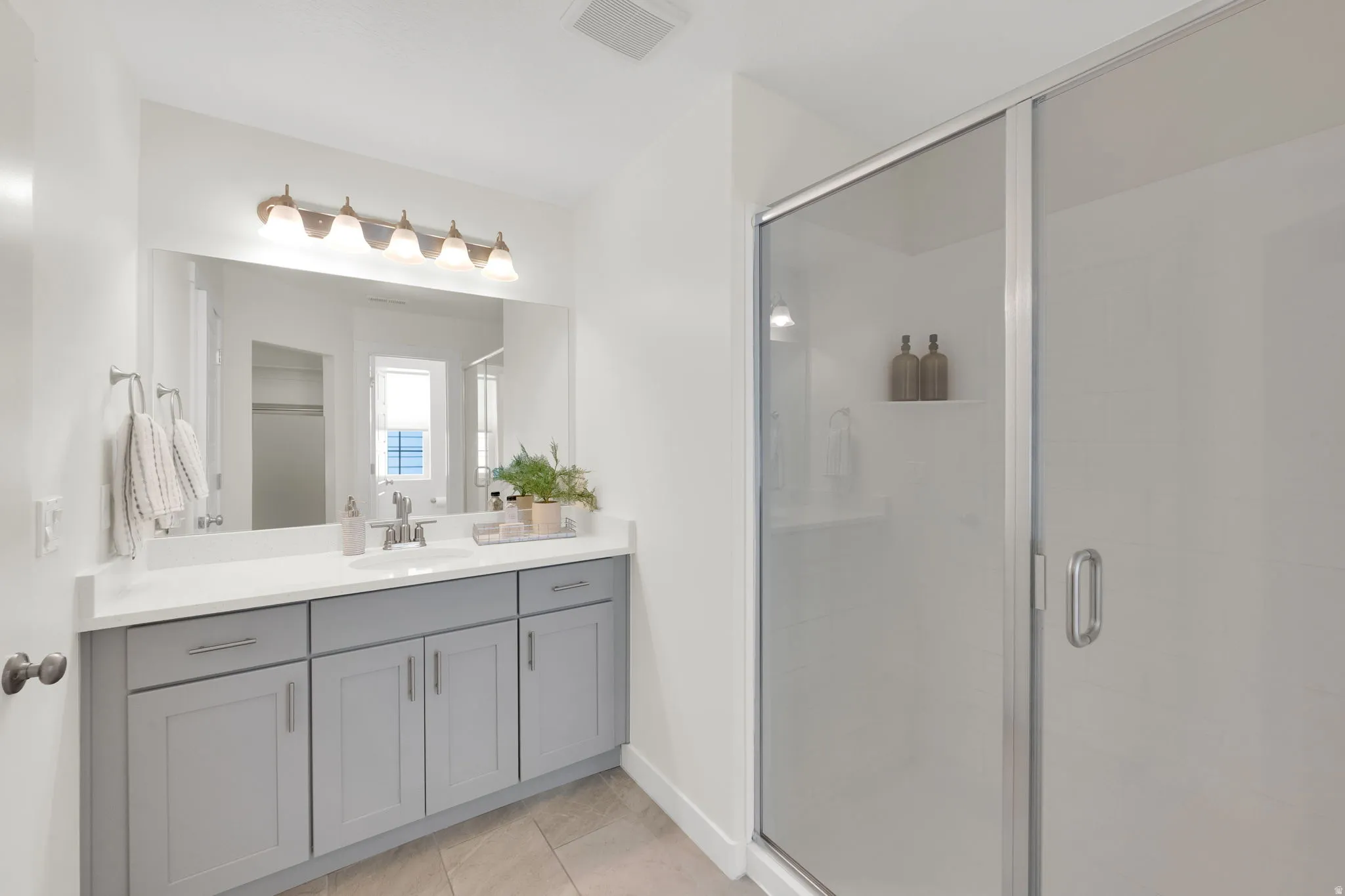 Primary Bathroom with vanity, a shower stall, and light tile patterned flooring