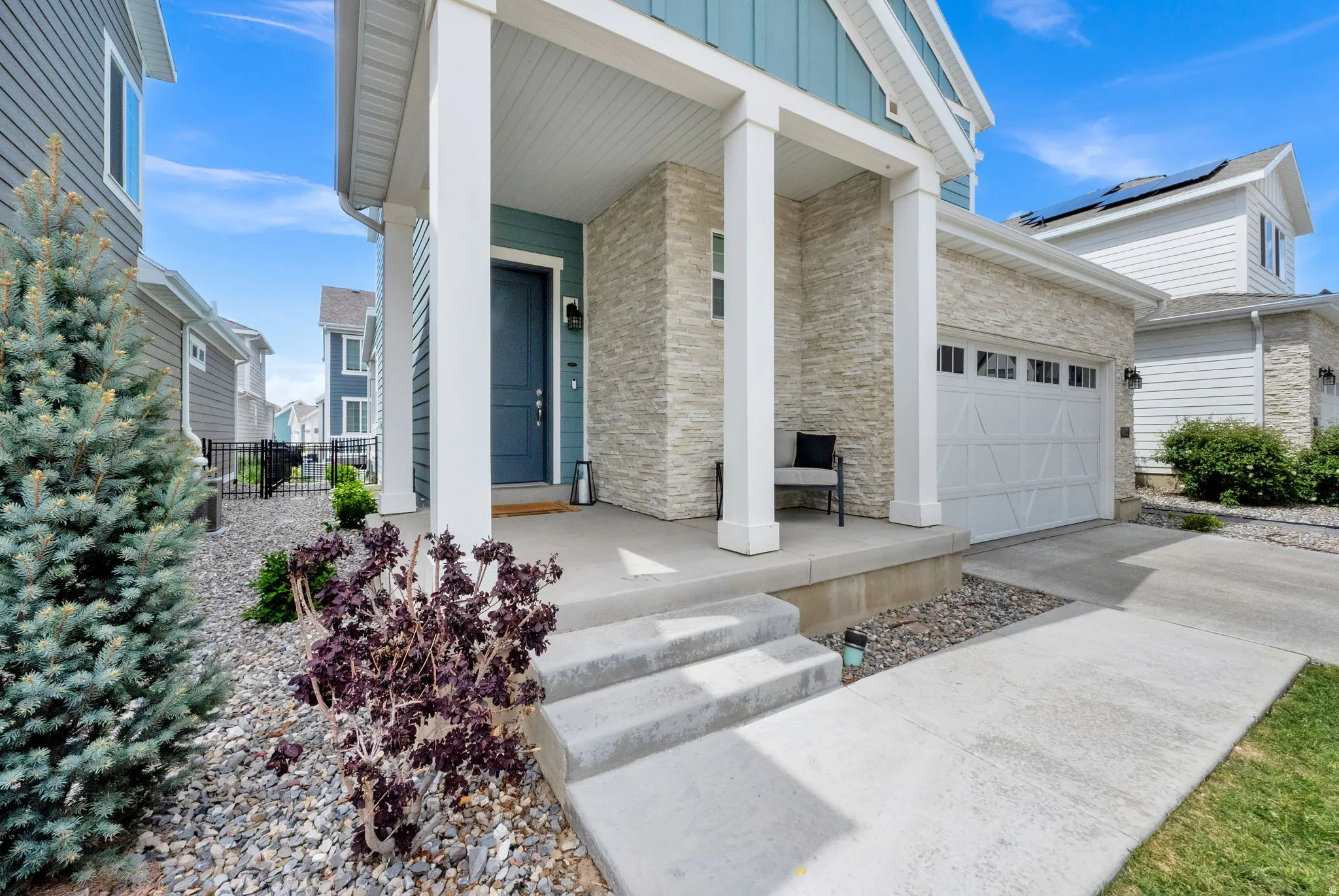 Property entrance featuring board and batten siding, stone siding, concrete driveway, covered porch, and a garage