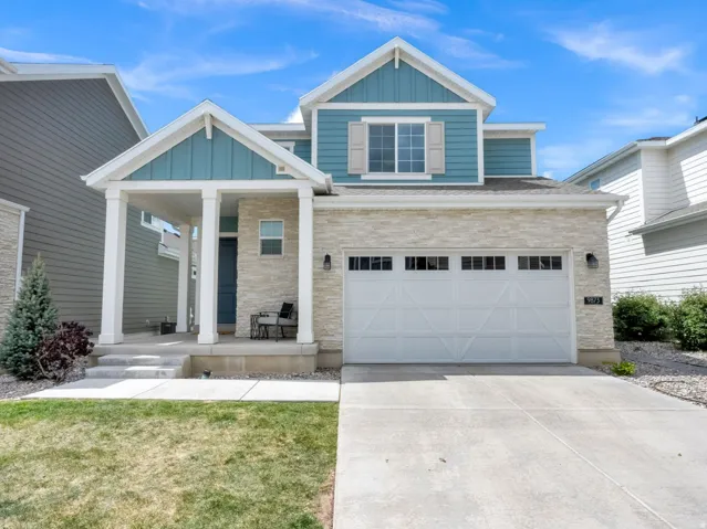 Craftsman house with board and batten siding, driveway, a garage, stone siding, and covered porch