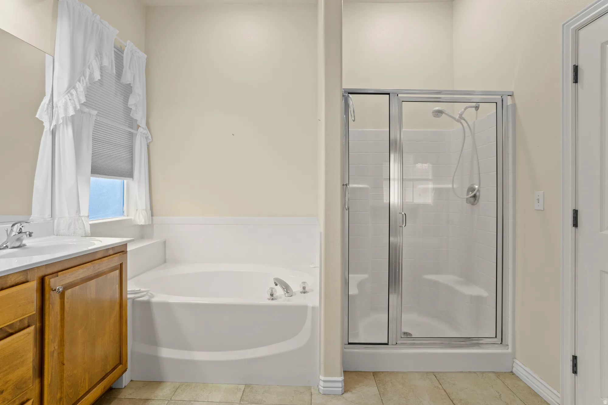 Full bathroom featuring vanity, a bath, a shower stall, and light tile patterned flooring