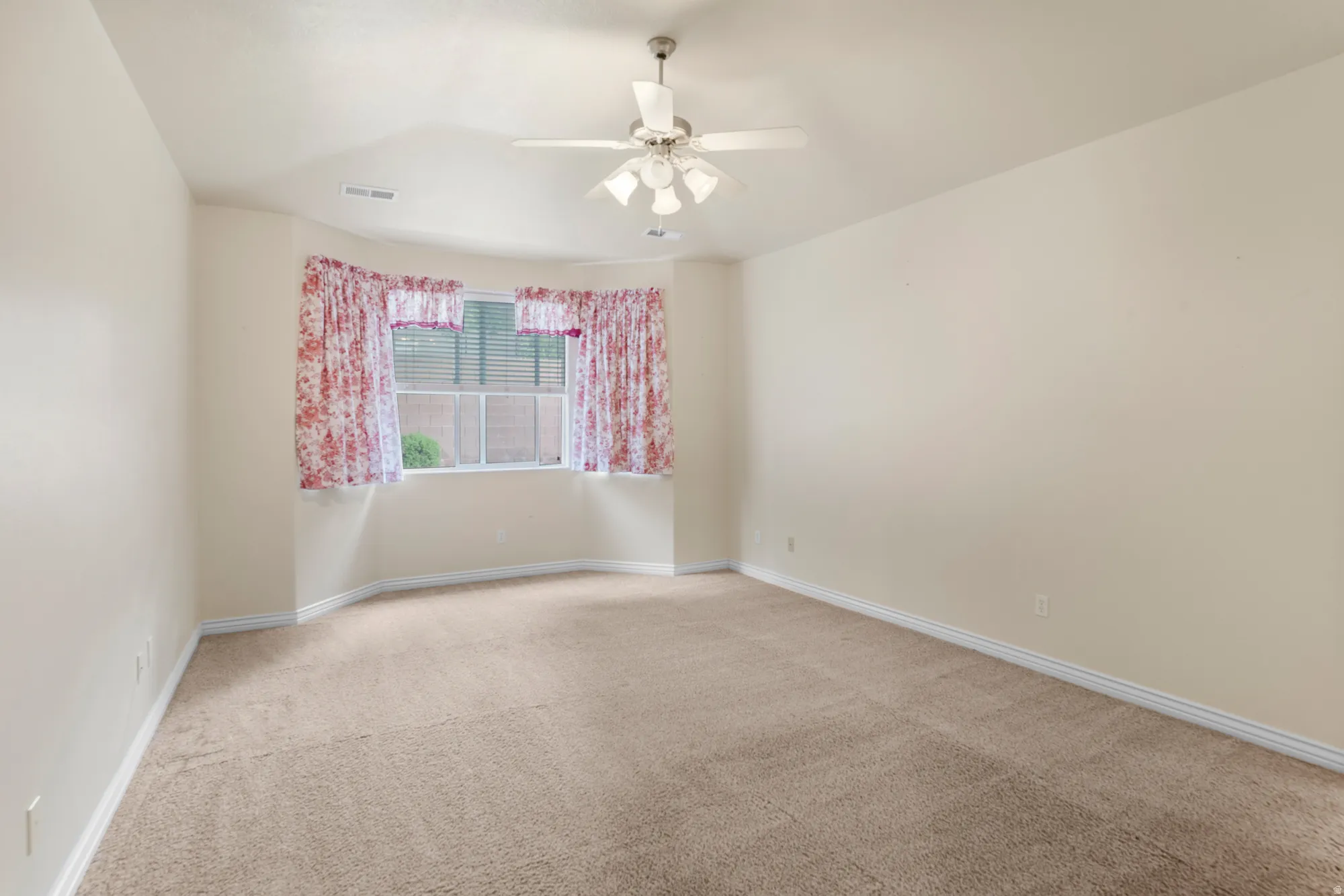 Empty room with light colored carpet and a ceiling fan