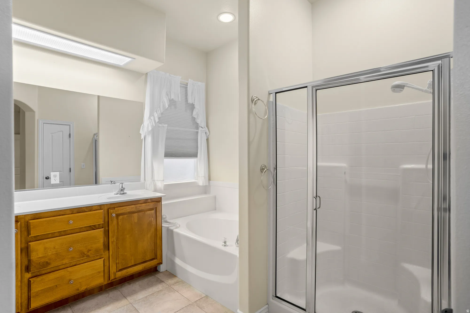 Full bathroom featuring vanity, a bath, a stall shower, and light tile patterned floors