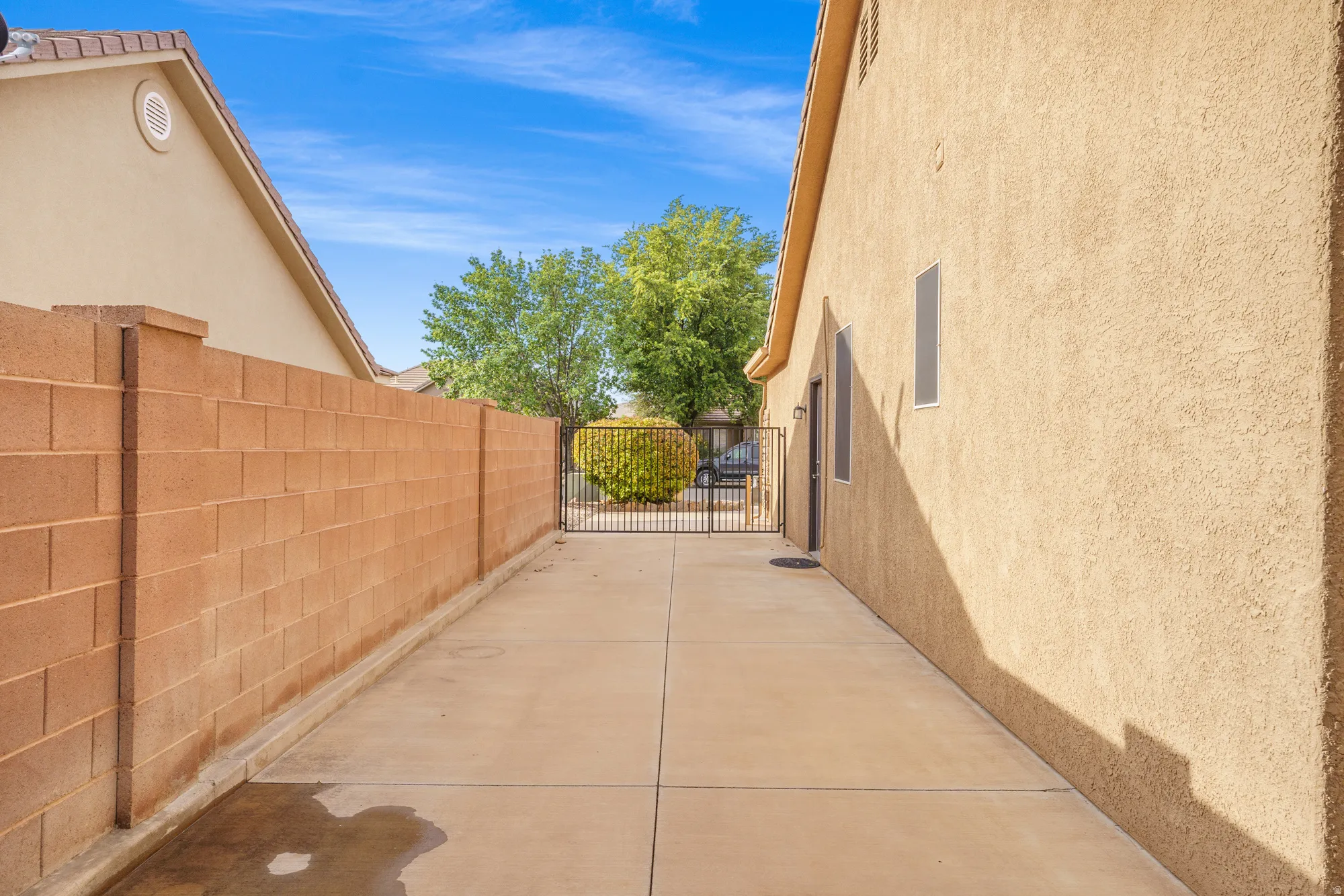 View of side of property with stucco siding and a gate