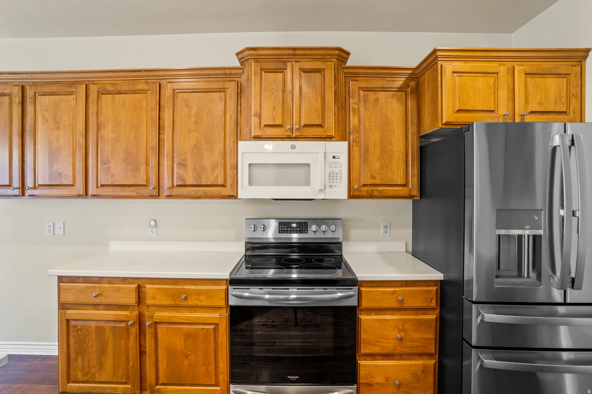 Kitchen with stainless steel appliances, light countertops, and wood finish cabinets