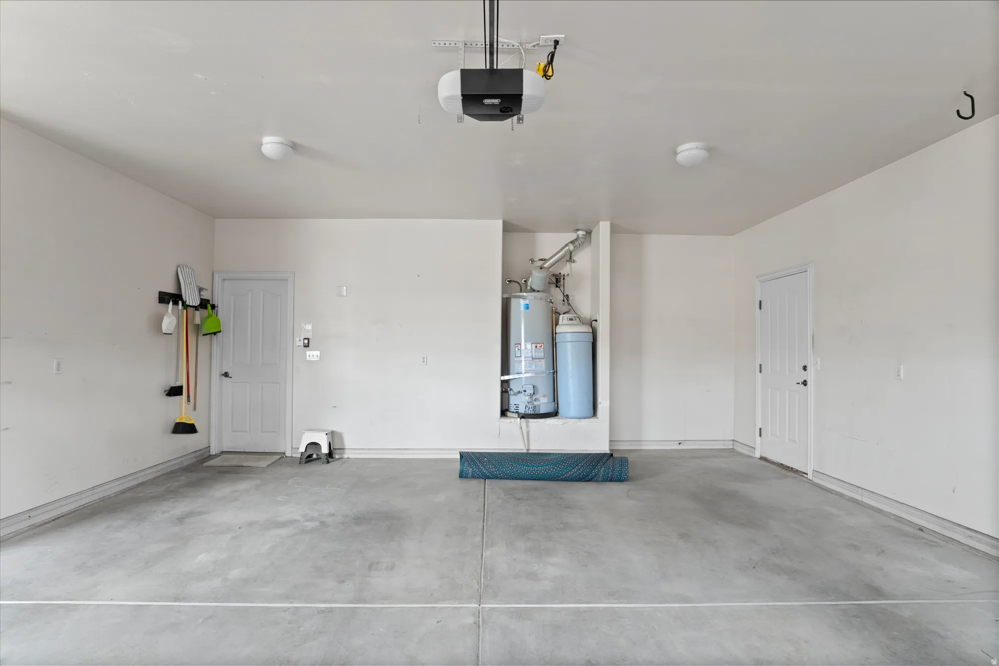 Garage featuring secured water heater and a garage door opener
