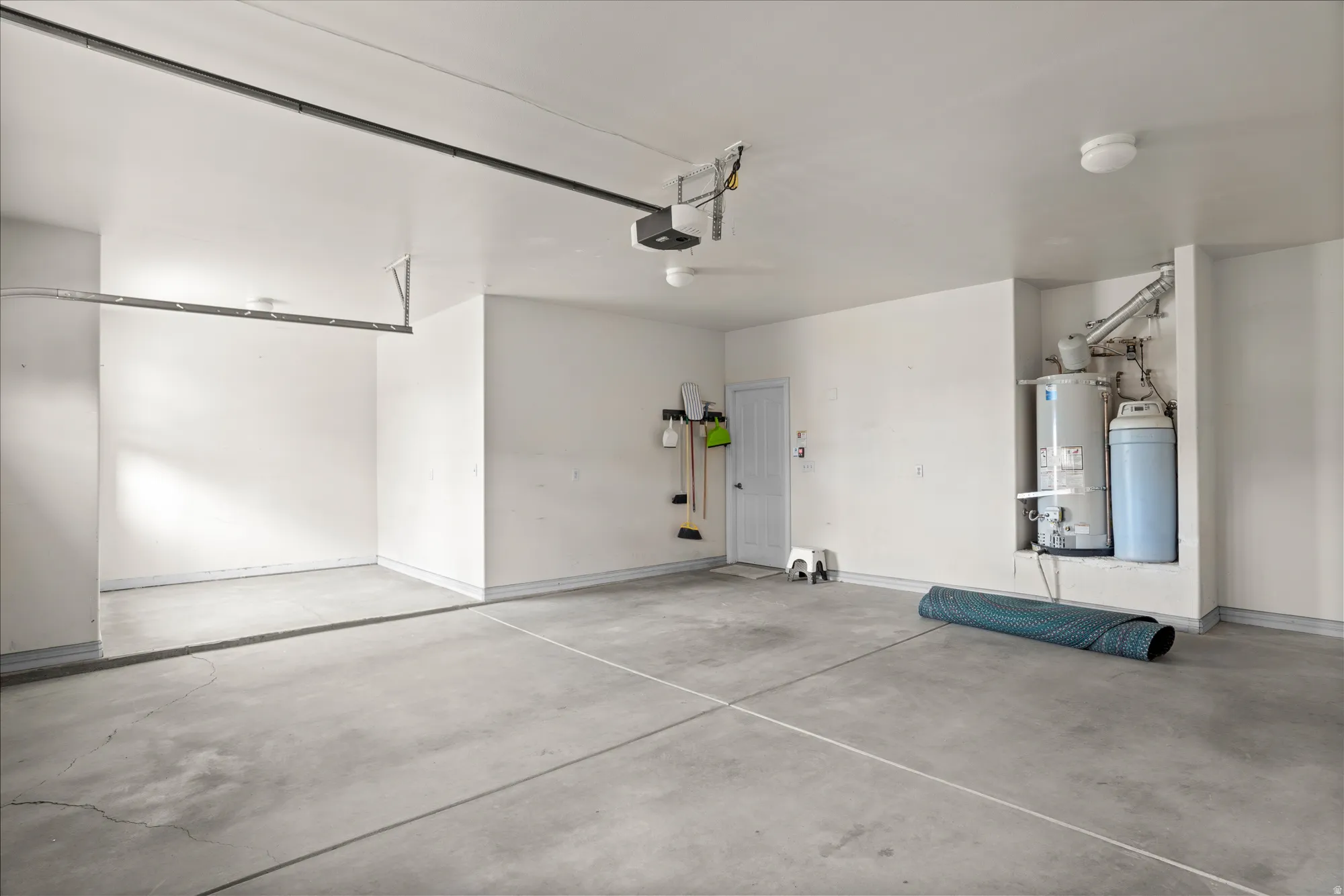 Garage featuring secured water heater and a garage door opener