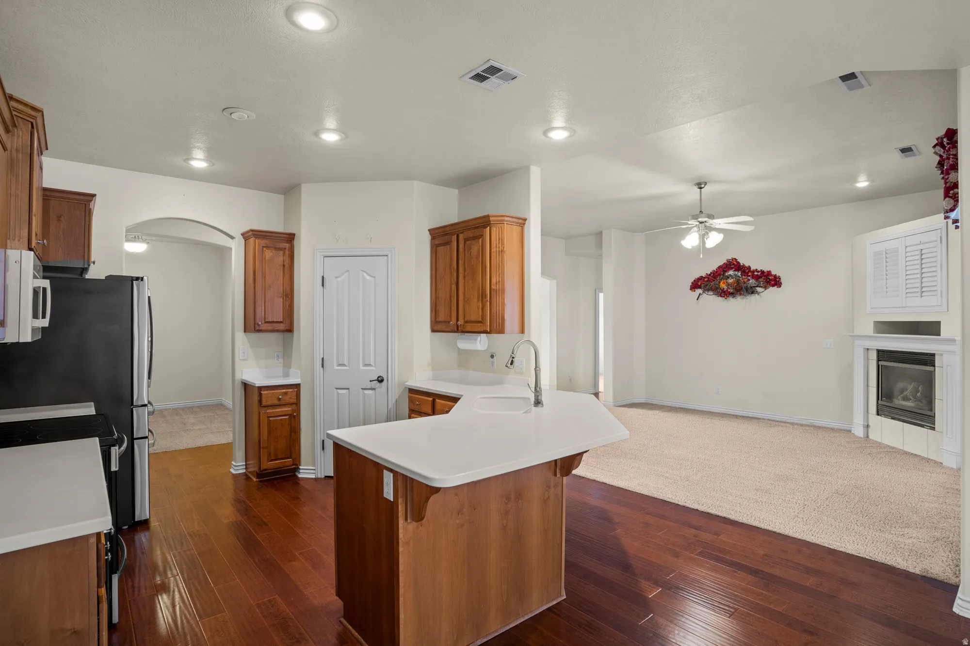 Kitchen with wood finish cabinets, a kitchen bar, light countertops, a peninsula, and open floor plan