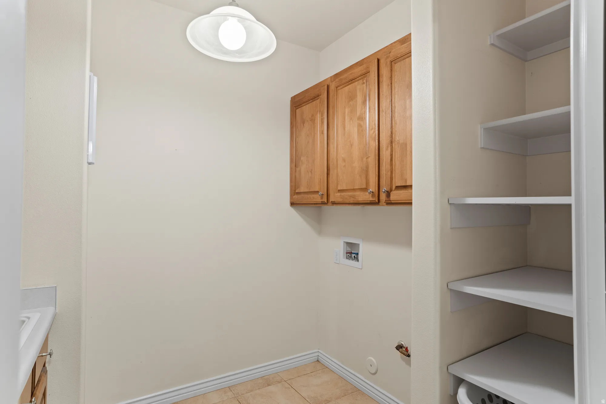 Laundry area featuring cabinet space, hookup for a washing machine, and light tile patterned floors