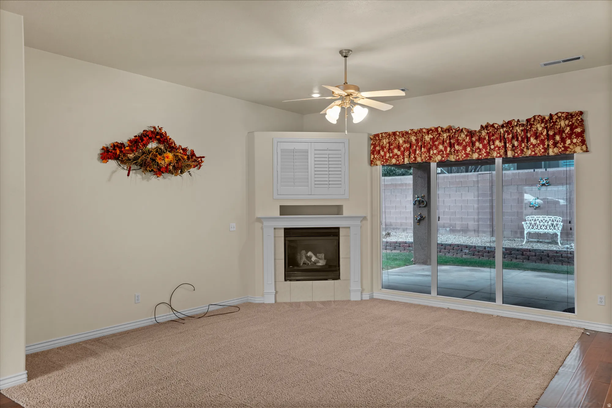 Unfurnished living room featuring a tile fireplace and a ceiling fan
