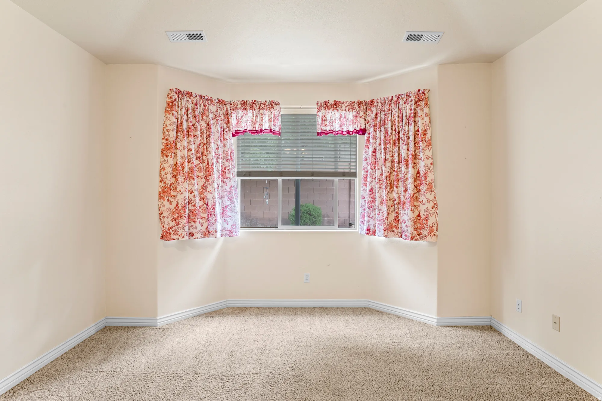 Empty room with light colored carpet and baseboards