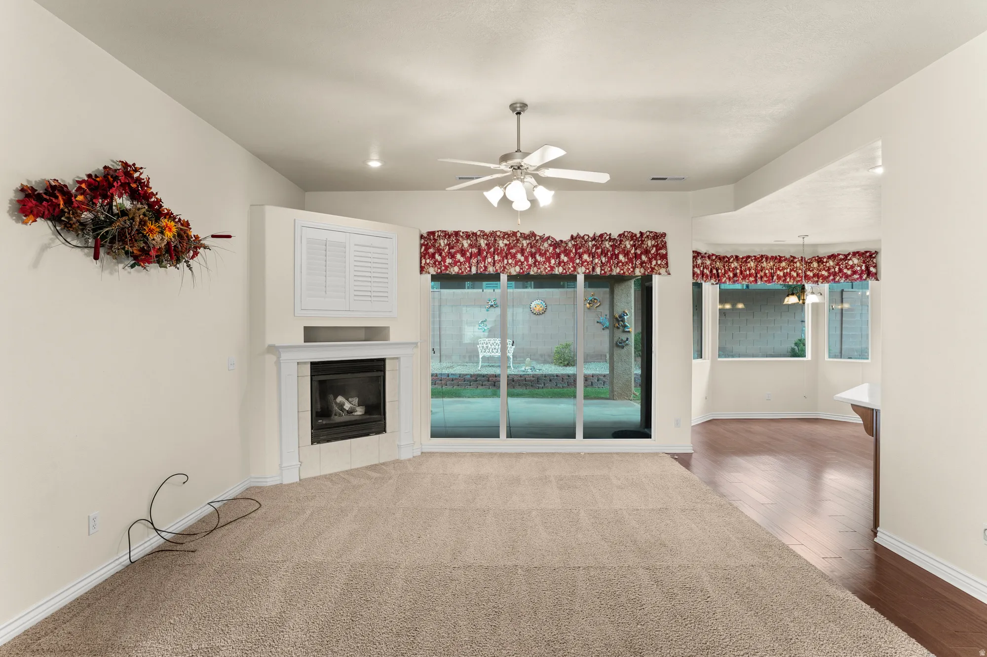 Unfurnished living room featuring a fireplace, ceiling fan, and dark wood-style floors