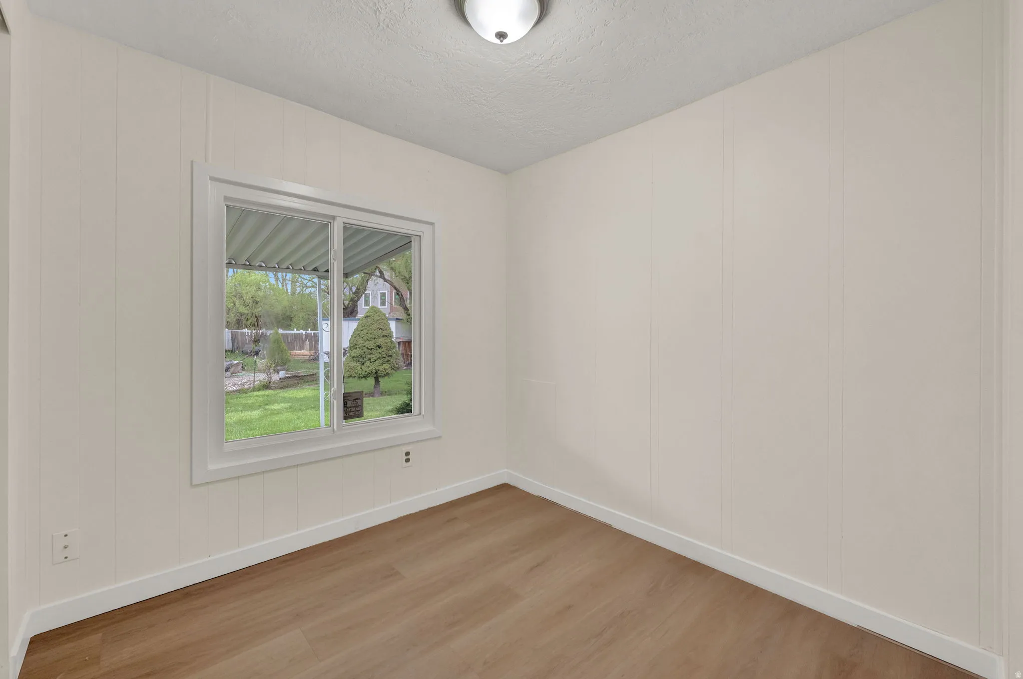 Spare room featuring light wood-type flooring, a textured ceiling, and a decorative wall