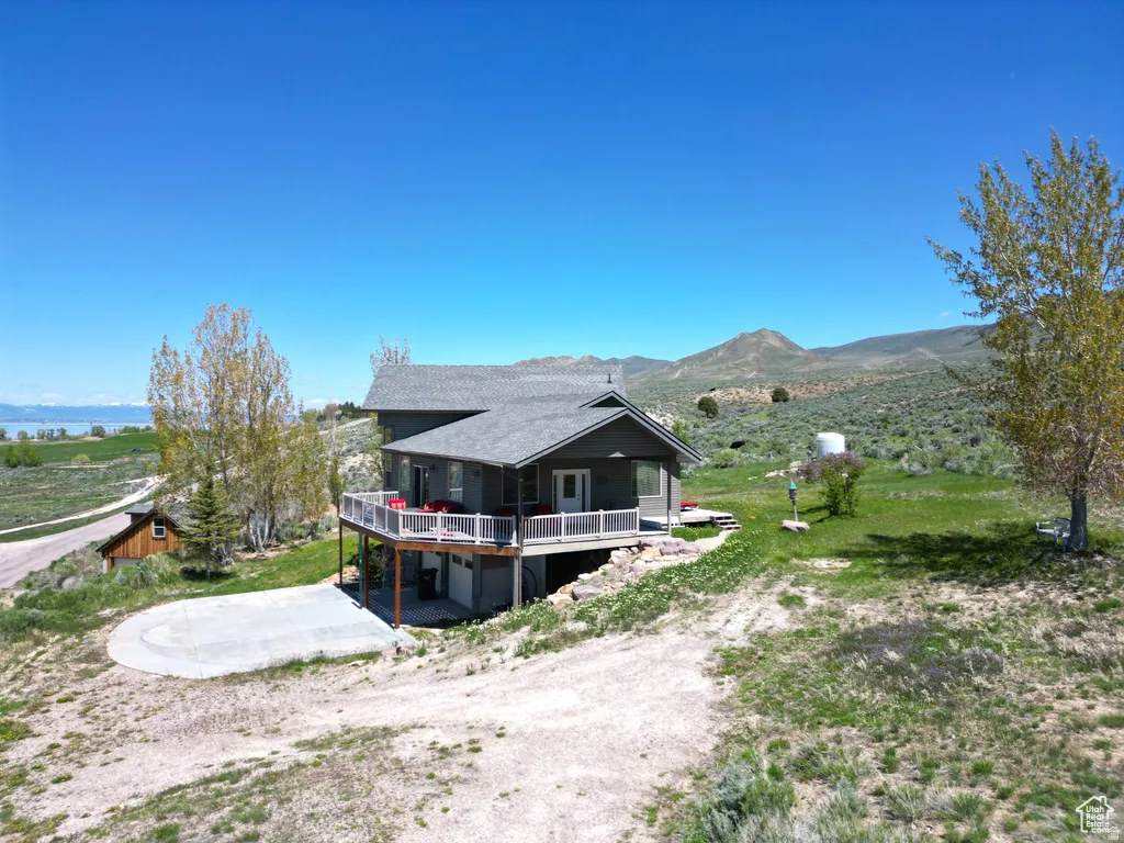 Back of property with a mountain view, an attached garage, driveway, and a view of countryside