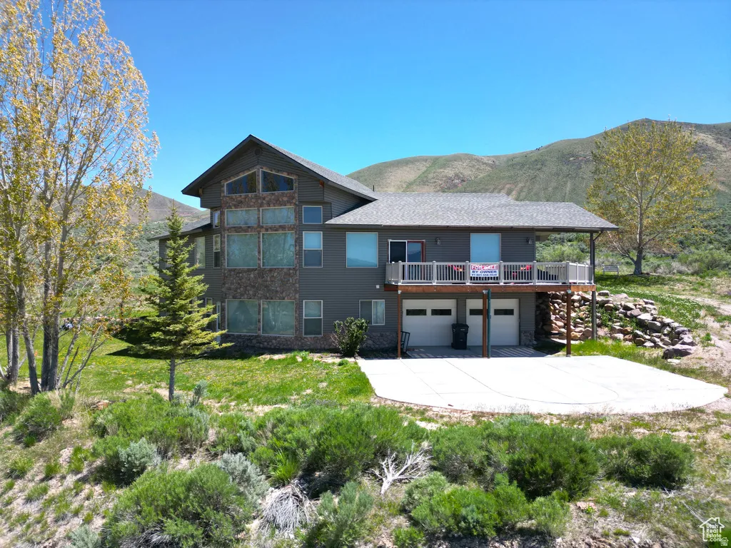 View of front facade with a mountain view, an attached garage, a patio area, a balcony, and driveway