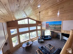 Living room featuring wooden walls, carpet floors, ceiling fan, and a vaulted wood ceiling