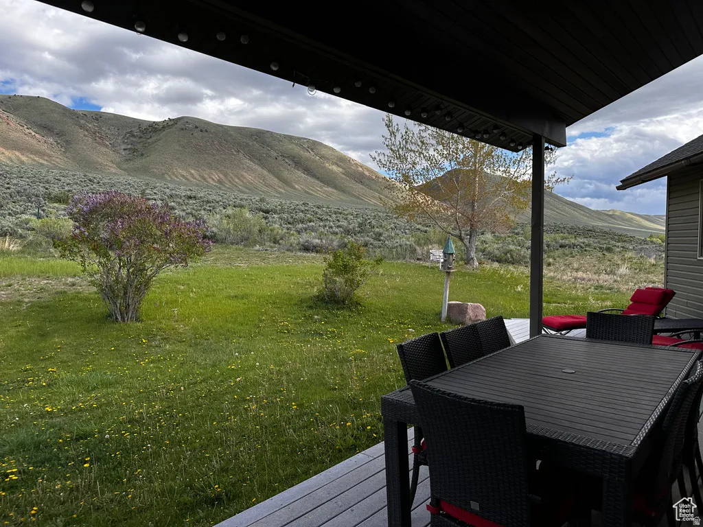 Wooden deck with a yard, outdoor dining area, and a mountain view