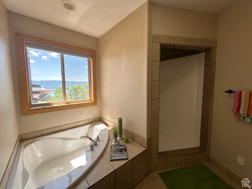 Full bathroom featuring a garden tub, a textured ceiling, a shower stall, and a mountain view
