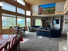 Carpeted living room featuring a vaulted wooden ceiling and wood walls