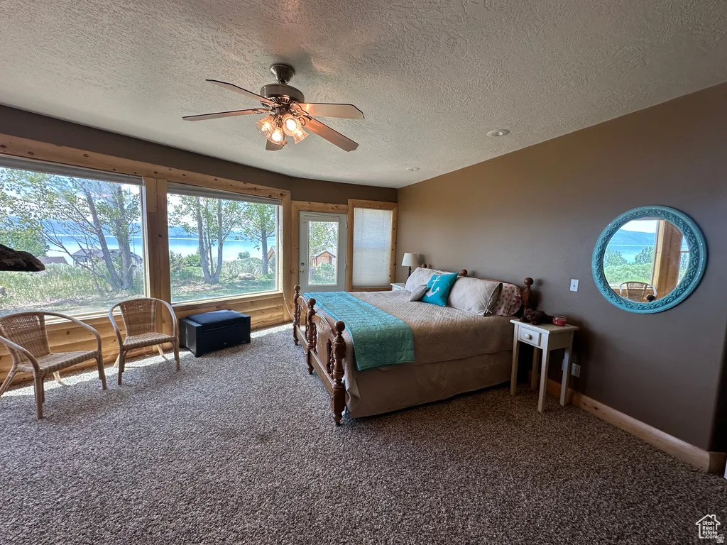 Carpeted bedroom with access to exterior, a textured ceiling, and ceiling fan